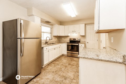 a kitchen with white cabinets and a stainless steel refrigerator