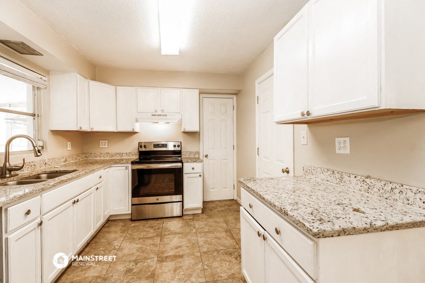 a large kitchen with white cabinets and granite counter tops