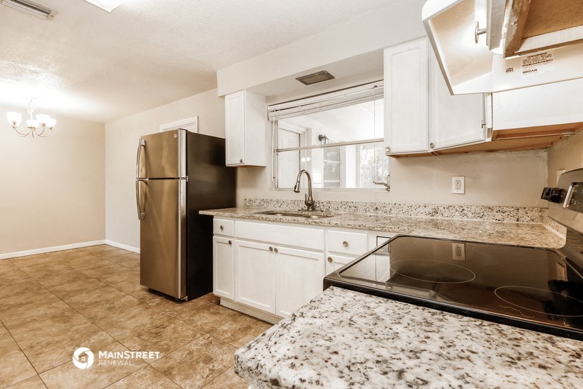 a kitchen with granite counter tops and a stainless steel refrigerator