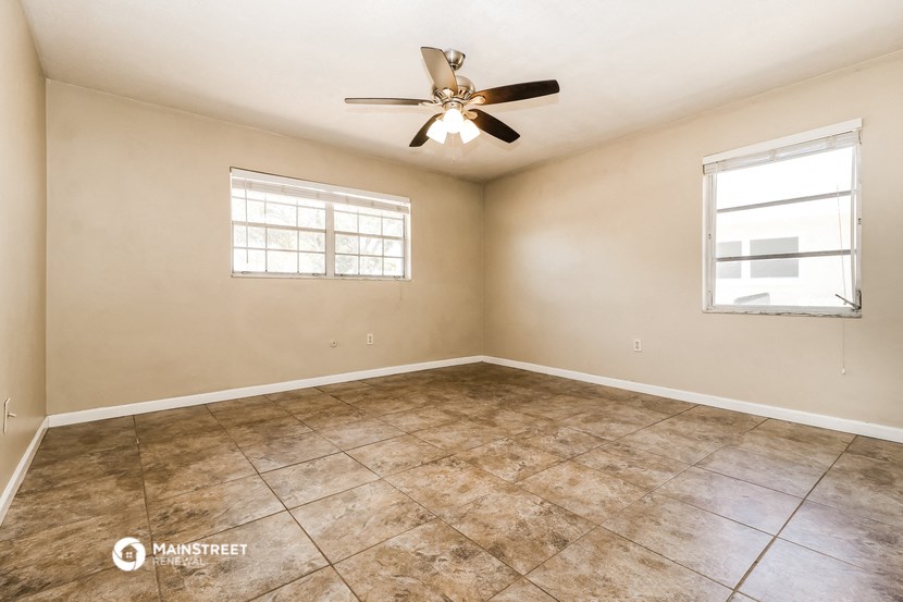 an empty living room with a ceiling fan and tiled floors