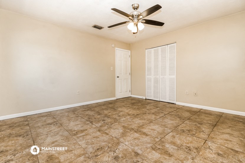 an empty living room with a ceiling fan and a door