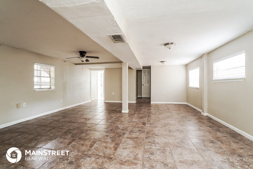 an empty living room with tile floors and a ceiling fan