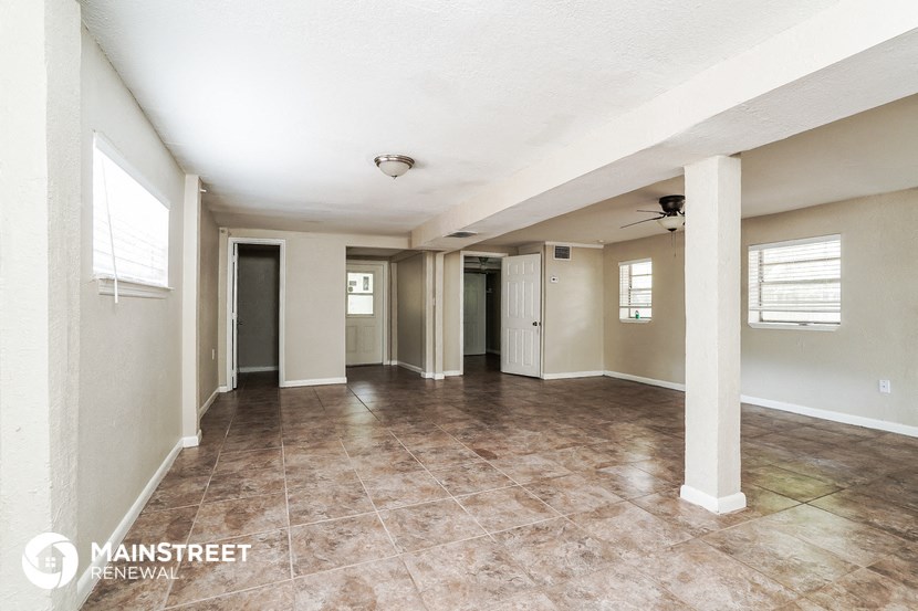 an empty living room with pillars and a tile floor