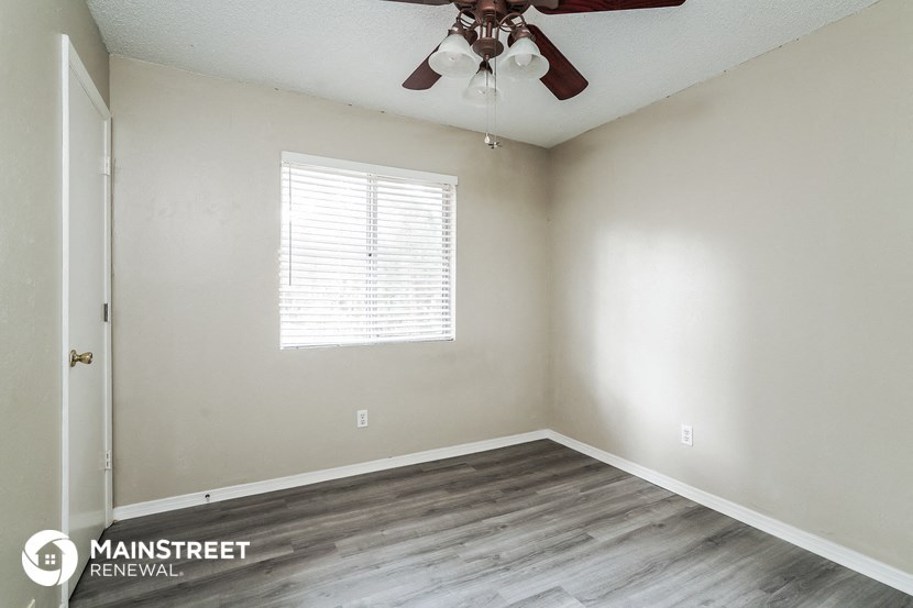 the spacious living room of a manufactured home with wood flooring and a ceiling fan
