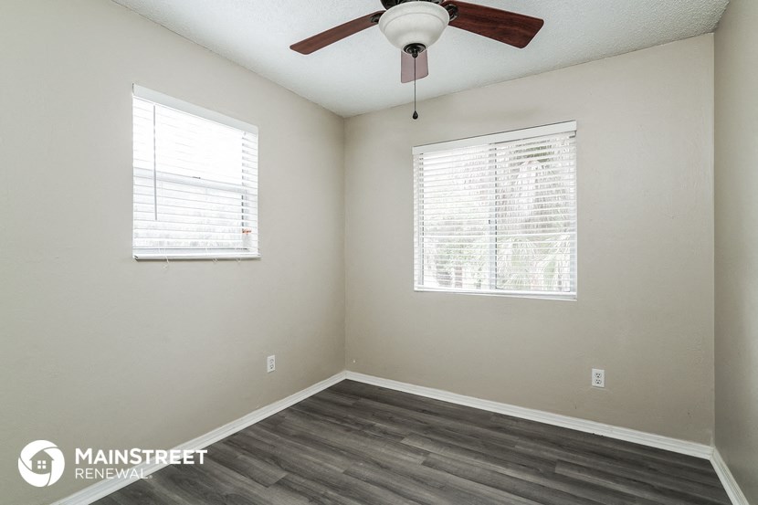 the interior of a room with wood flooring and a ceiling fan