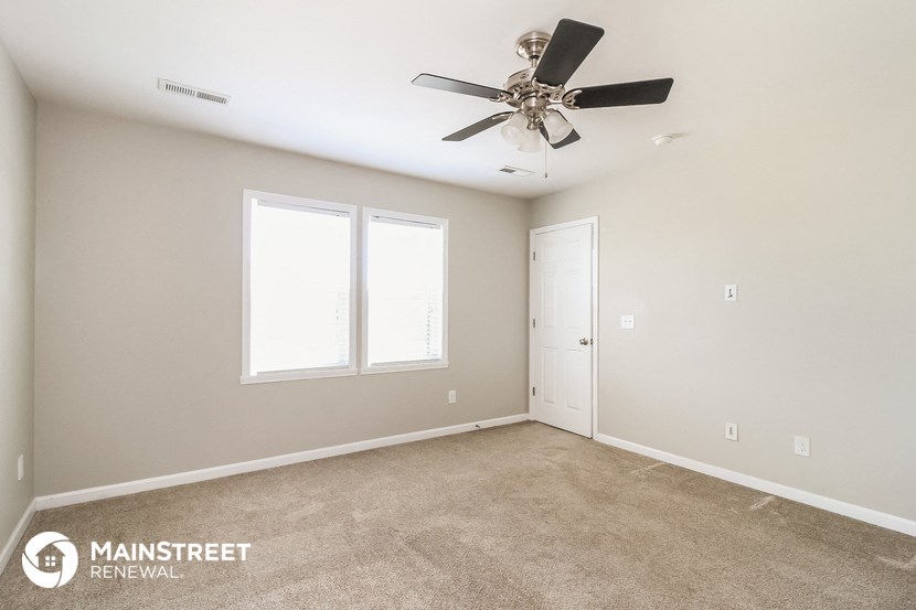 the master bedroom has carpeted floors and a ceiling fan