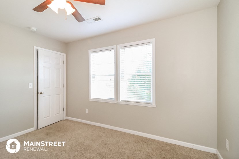 a bedroom with two windows and a ceiling fan