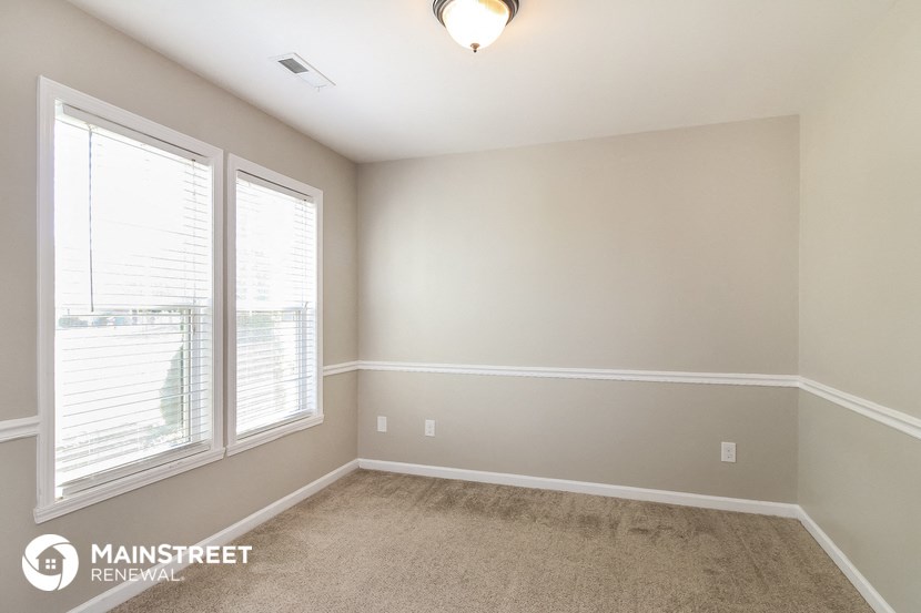 the spacious living room with two windows and carpeted flooring