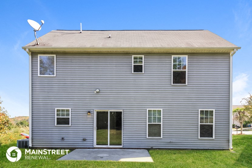 the front of a gray house with a satellite dish on the roof