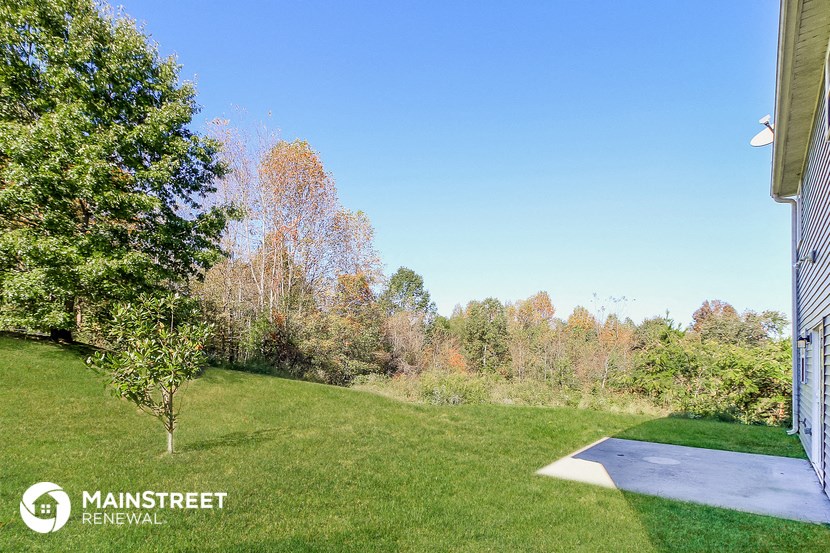 a backyard with green grass and trees and a blue sky