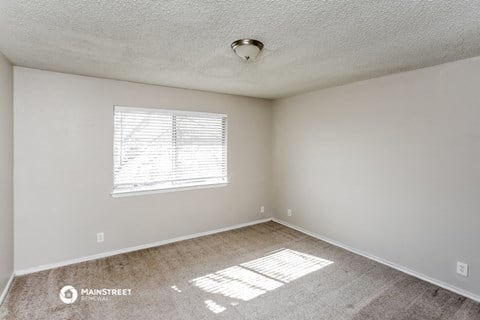 the spacious living room of a manufactured home with carpet and a window