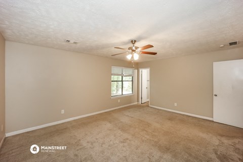 the spacious living room with ceiling fan and carpet