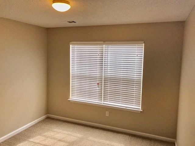 an empty room with a window and a lamp on the ceiling