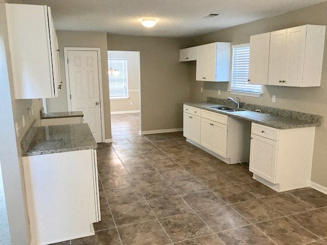 an empty kitchen with white cabinets and a sink