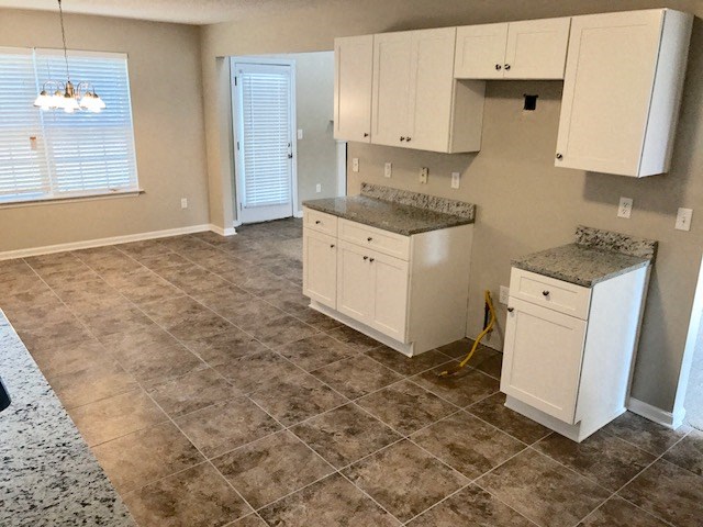 an empty kitchen with white cabinets and tile floors
