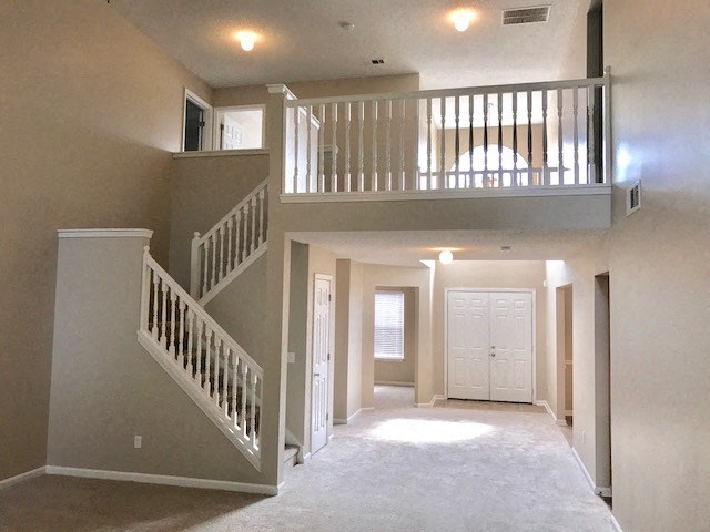 an empty living room with a staircase and a white door