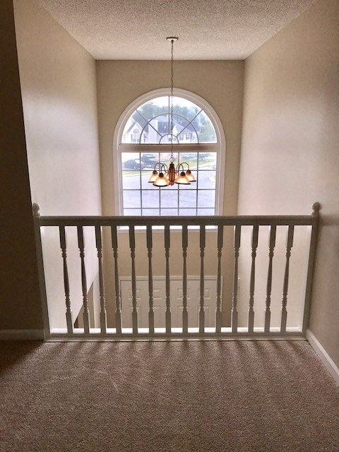 an empty staircase with a window and a chandelier