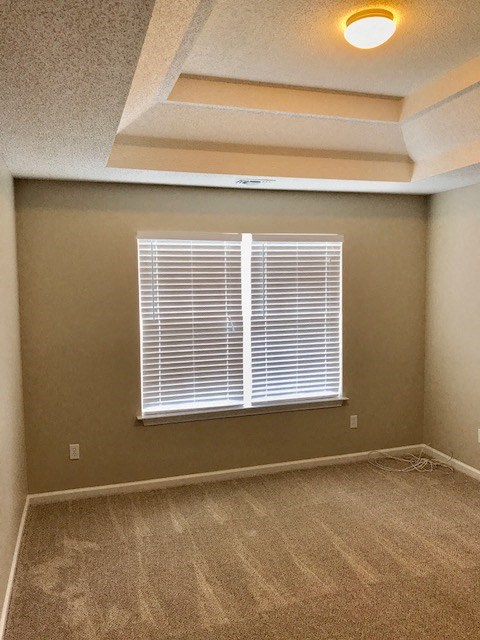 an empty living room with a window and carpet