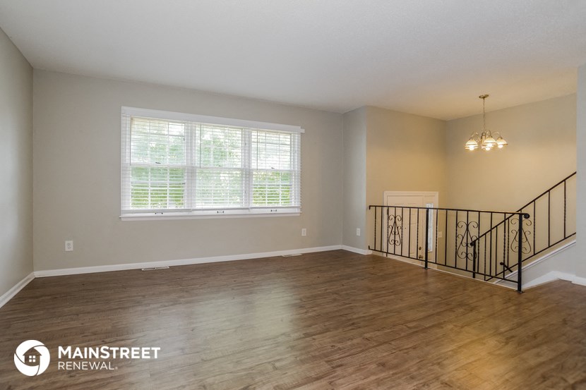 the living room of a house with a staircase and a large window