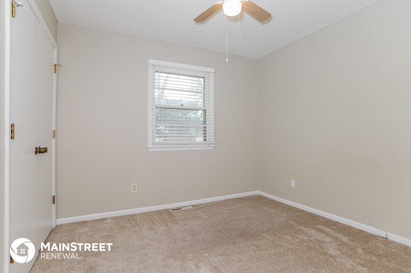 an empty room with a ceiling fan and a window