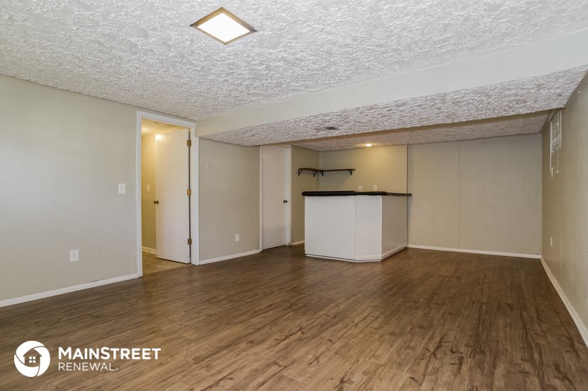 the spacious living room with wood flooring and a kitchen