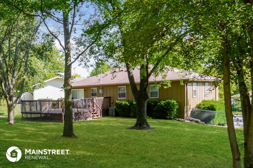 a home with a deck and trees in front of it