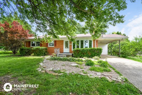 a house with a driveway and a lawn and trees