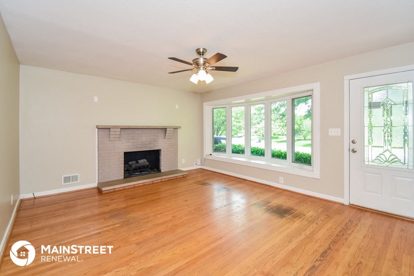 the living room with wood floors and a fireplace and a ceiling fan
