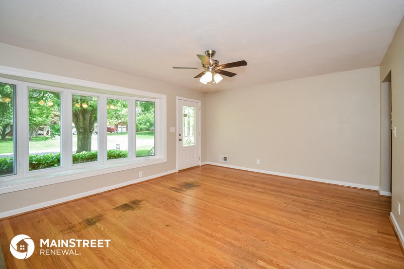 the living room with wood floors and a ceiling fan