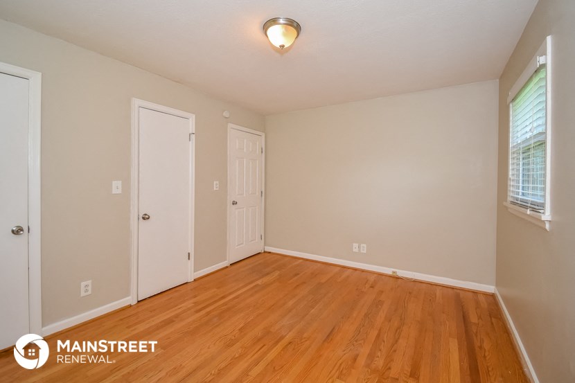 the upstairs bedroom with hardwood flooring and a door to the bathroom
