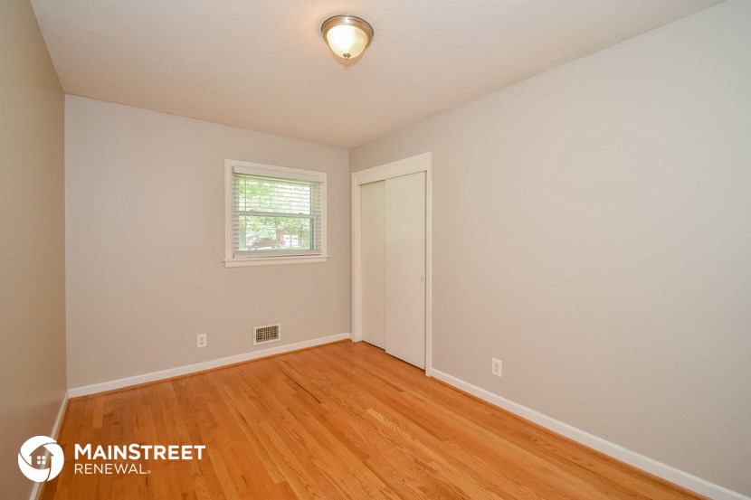 the upstairs bedroom with hardwood flooring and a window