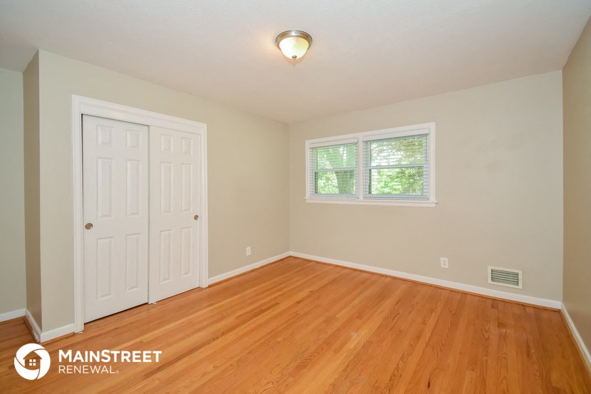 the bedroom of a home with wood floors and a white door