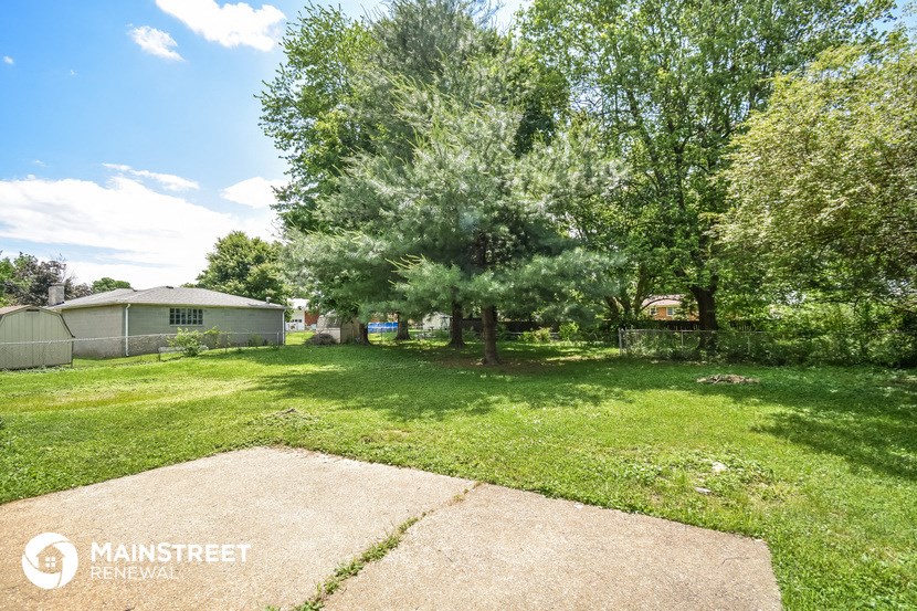 a yard with trees and a house in the background