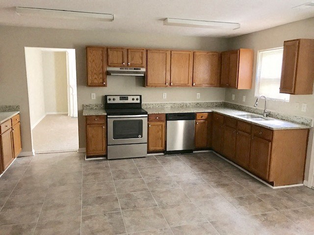an empty kitchen with wooden cabinets and stainless steel appliances