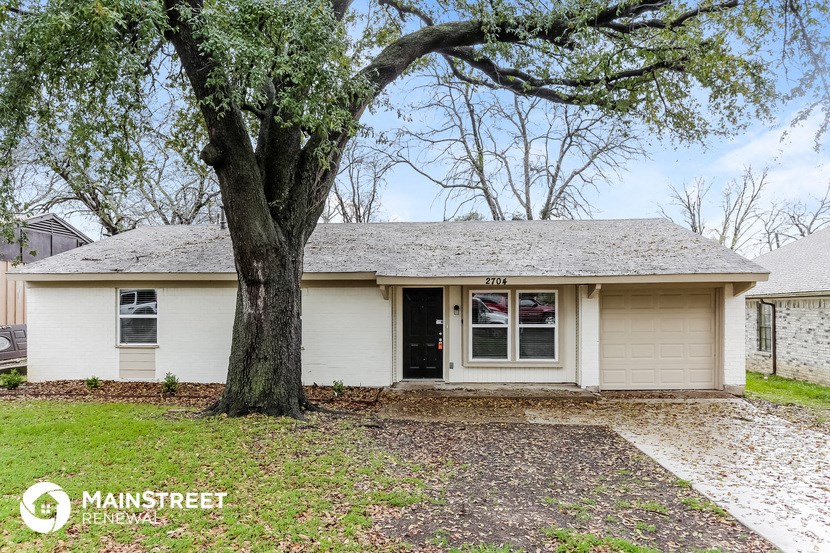 a white house with a large tree in front of it