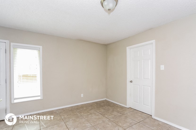 the living room of a home with a tile floor and a white door