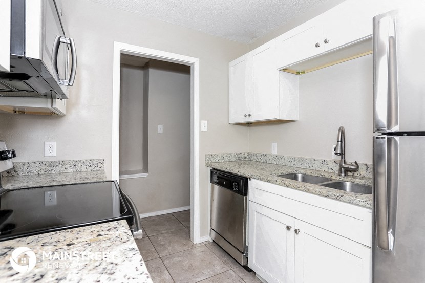a white kitchen with stainless steel appliances and granite counter tops