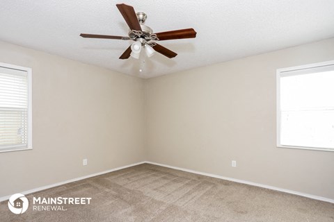 a living room with carpet and a ceiling fan