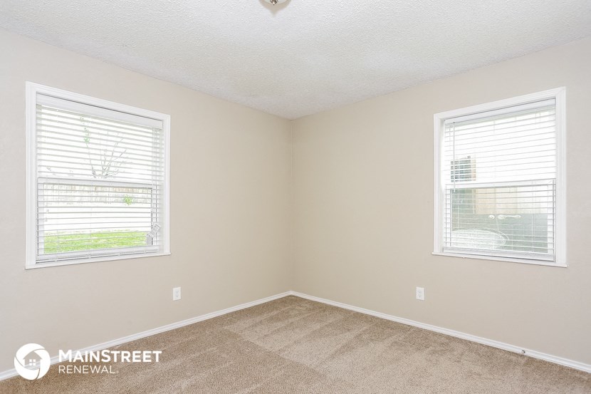 a bedroom with two windows and a carpeted floor
