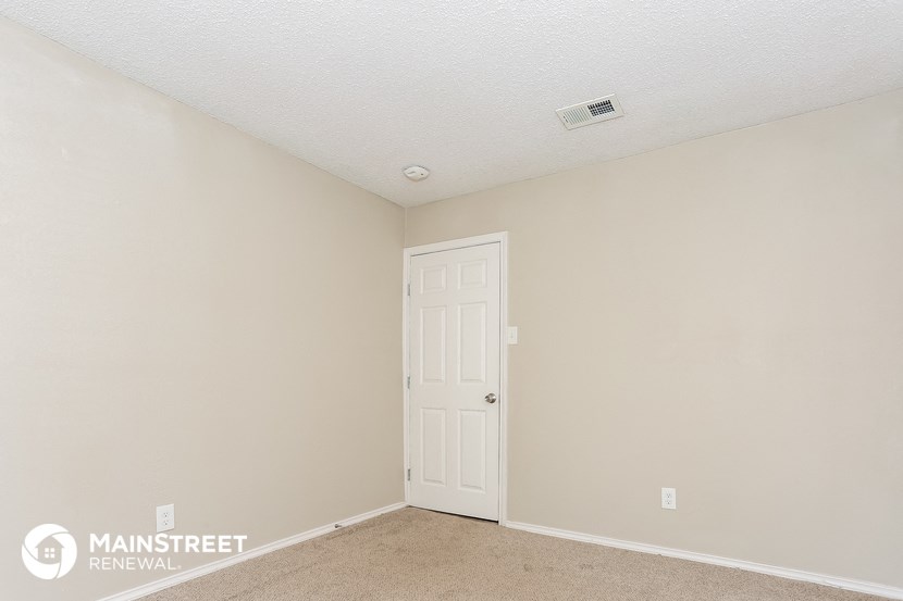 a bedroom with a white door and beige walls and carpet