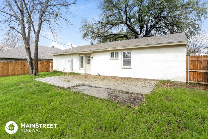 a backyard with a white house and a yard with a sidewalk