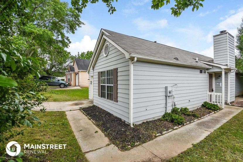 a small white house with a sidewalk in front of it