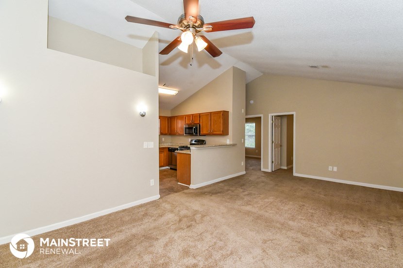 a living room with a ceiling fan and a kitchen