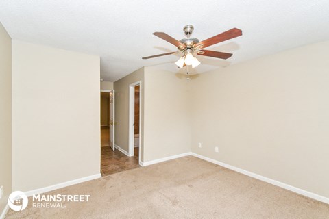 the spacious living room with ceiling fan and carpet