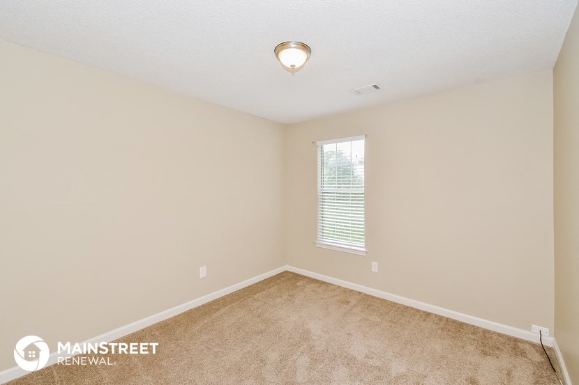 the spacious living room with carpeting and a window