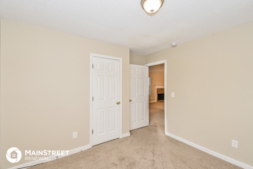 a living room with two doors and a hallway to a bedroom
