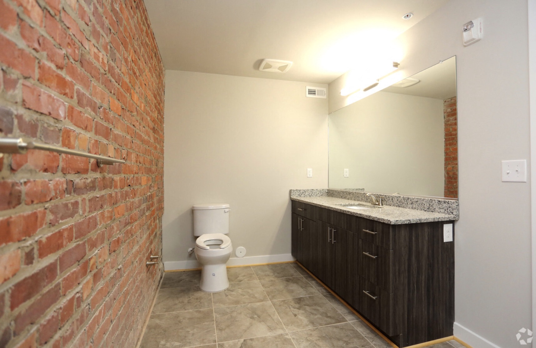a bathroom with a brick wall and a sink and a toilet