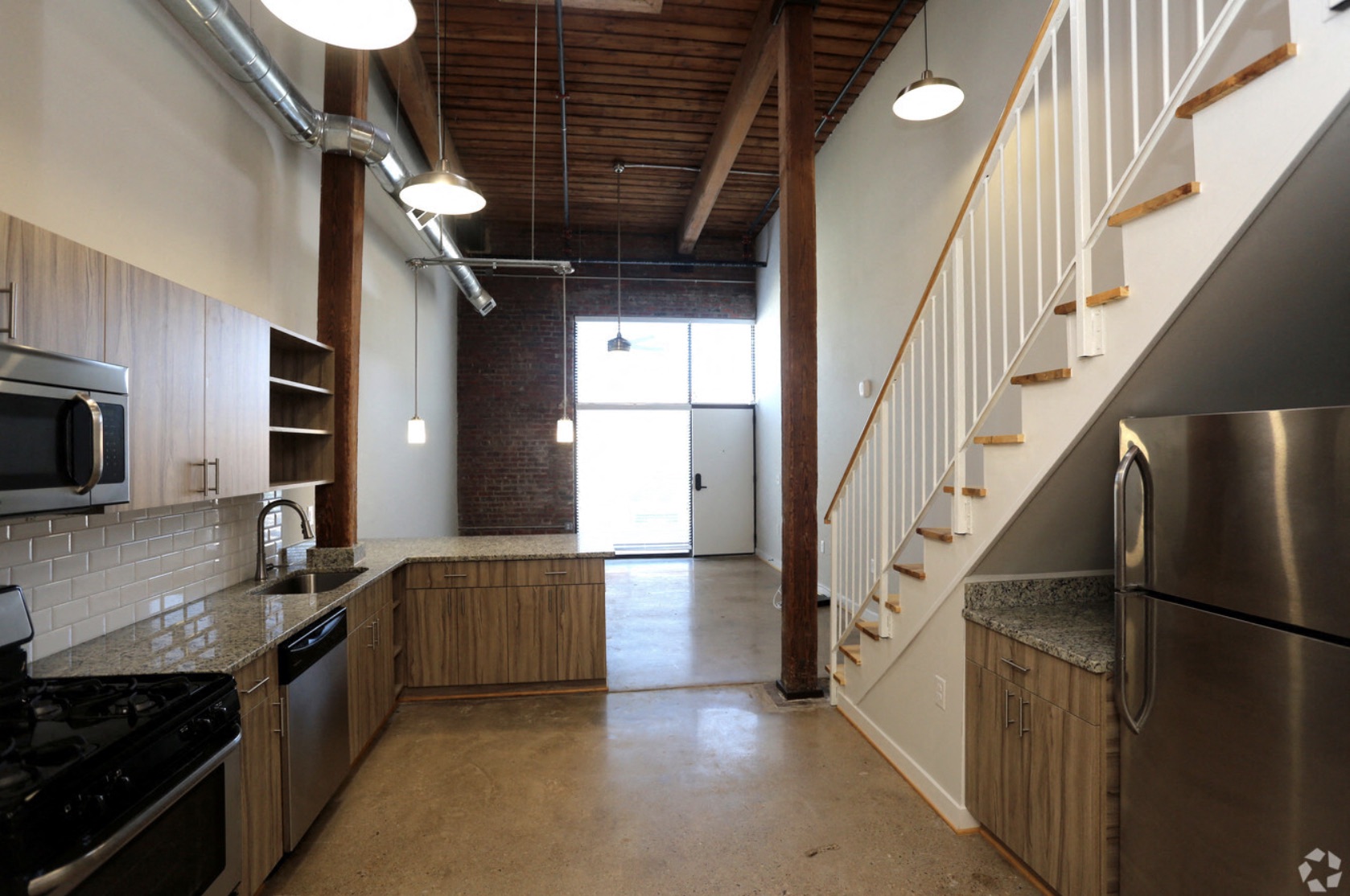 a kitchen with a stainless steel refrigerator and a staircase