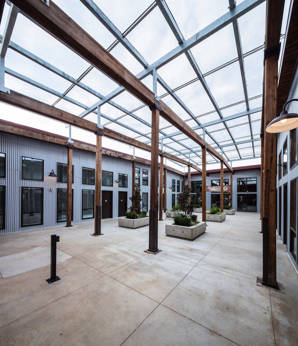 the courtyard of a building with a glass ceiling and planters