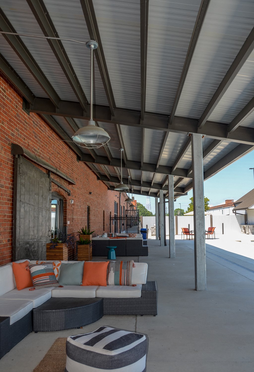 a long porch with couches and a table and chairs under a roof